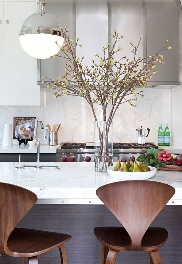 Nam Dang Mitchell's design of a kitchen with urban rustic vibes, including white marble counters and dark wood stools.