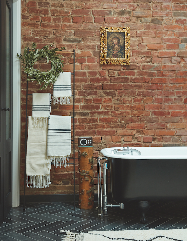 Rustic and industrial bathroom with exposed brick wall and black tub