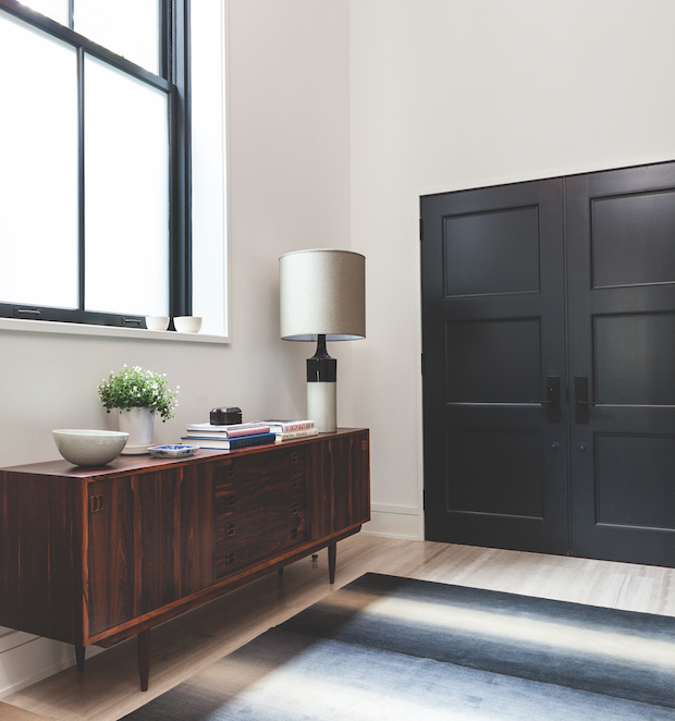 Sleek entryway with a gradient rug and black doors