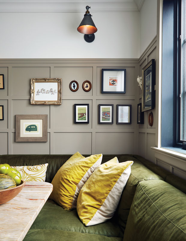 Breakfast nook with velvet banquette, a gallery wall and black sconces