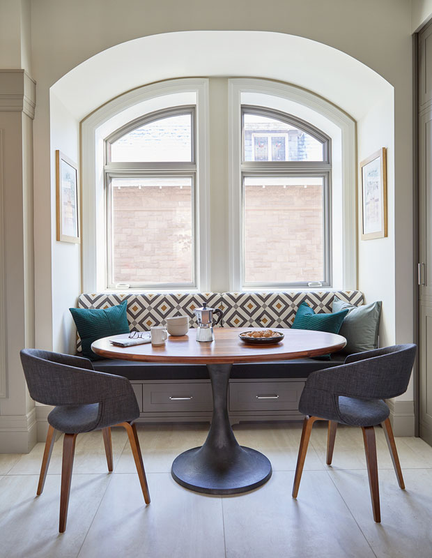 Breakfast nook with patterned banquette, circular wooden table and cut-out chairs