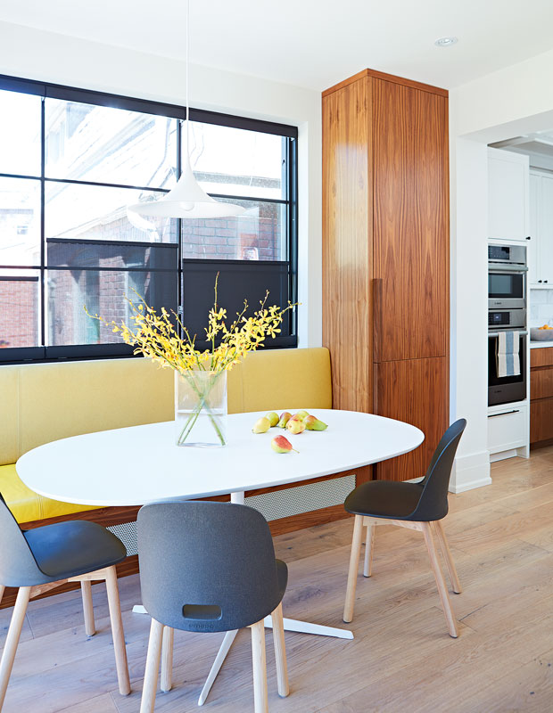 Breakfast nook with a bright yellow banquette, gunmetal chairs and a sleek white table