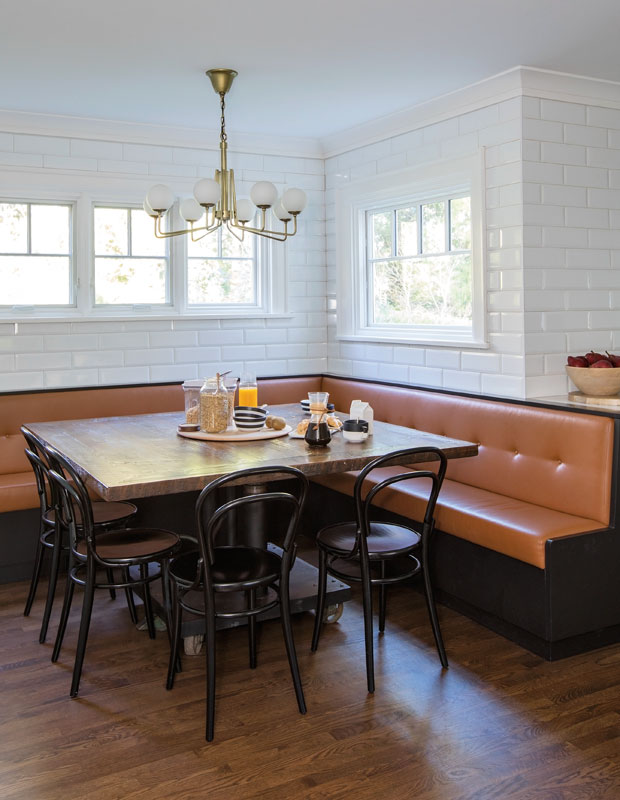 Breakfast nook with burnt orange leather banquette, old-fashioned restaurant chairs and a subway tile walls