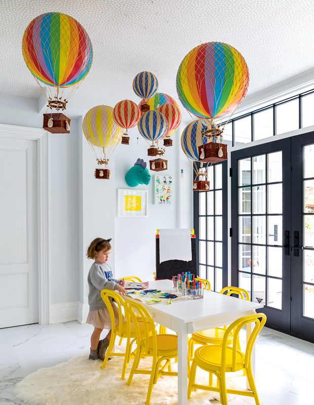 Organized family homes colorful playroom with rainbow hot air balloons and yellow chairs