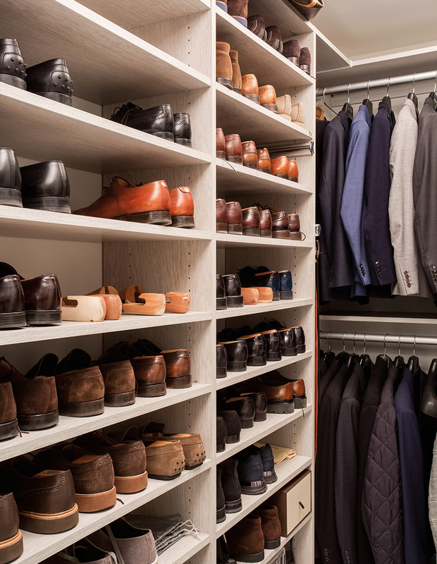 Organized walk-in men's closet with suits and dress shoes