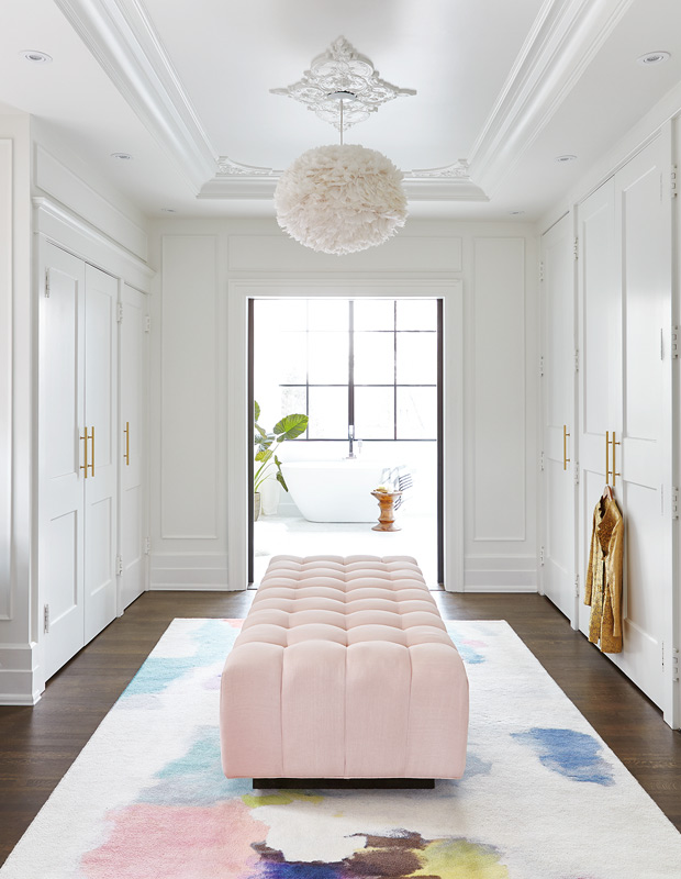 Organized walk-in closet - pink tufted bench with watercolor rug