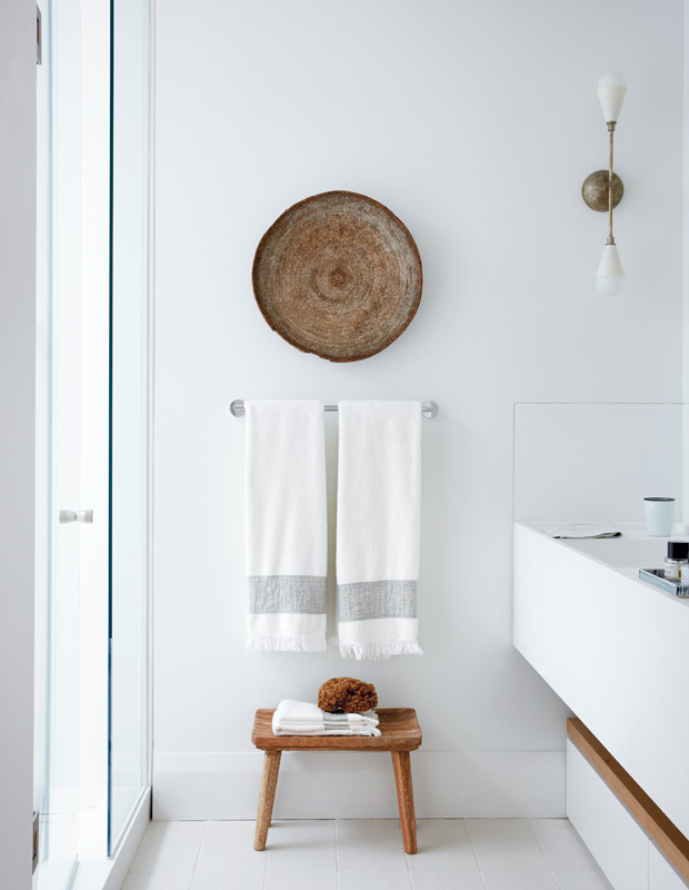 Minimalist spaces bathroom with a simple towel rack and wooden stool