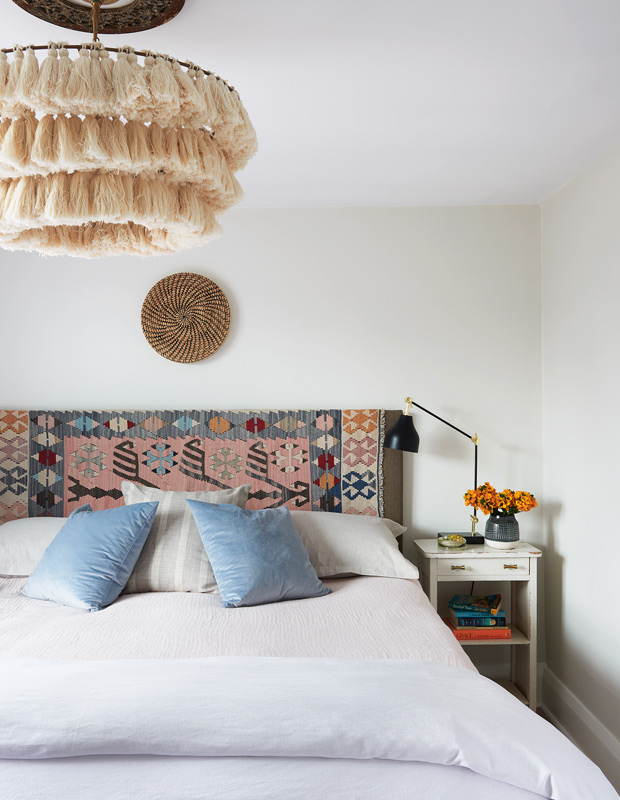 Global style bedroom with rug headboard and tassel light fixture