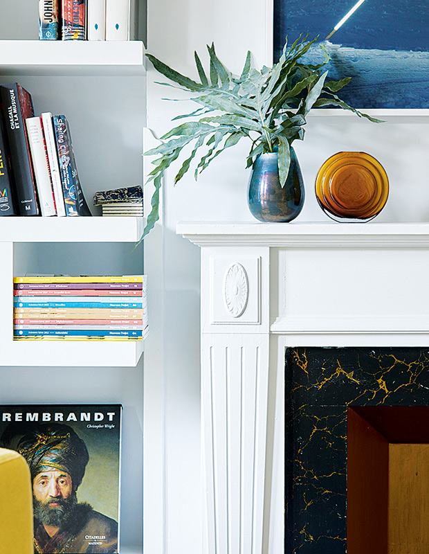 Colourful Montreal Home fireplace mantel with an intricate vase and built-in bookshelf