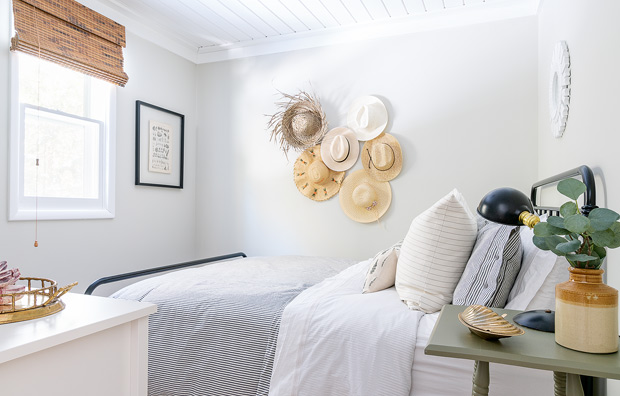 Lakeside cottage makeover principal bedroom with a collection of hats hanging on the wall