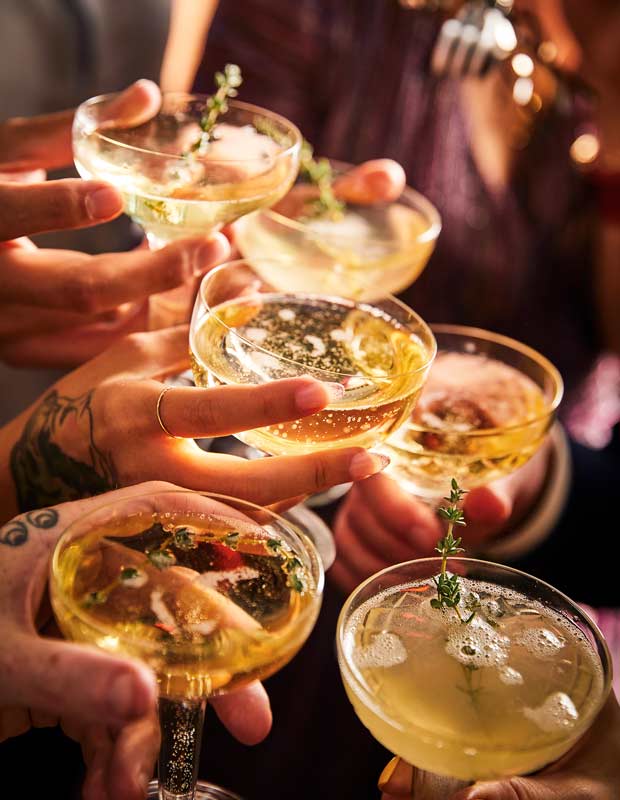 Close-up of hands holding French 227 cocktails
