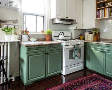 A kitchen with cabinets painted green and white.