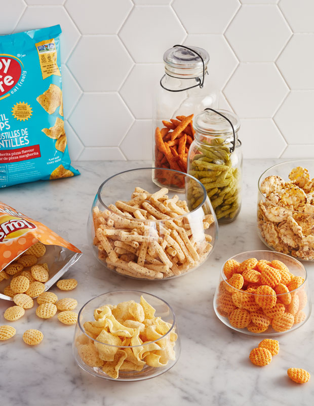 Bowls and jars of crunchy puffed snacks on a counter.
