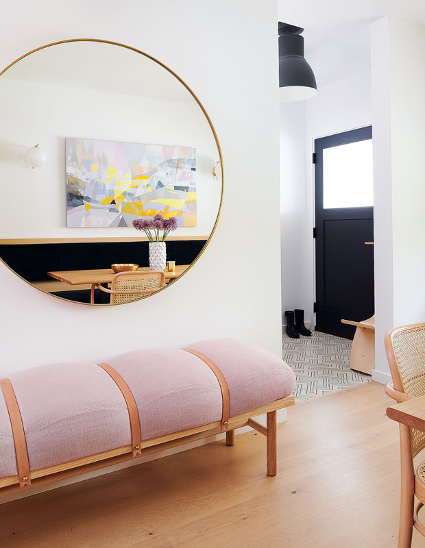 decorated minimalism entryway with a plush pink bench and large round mirror