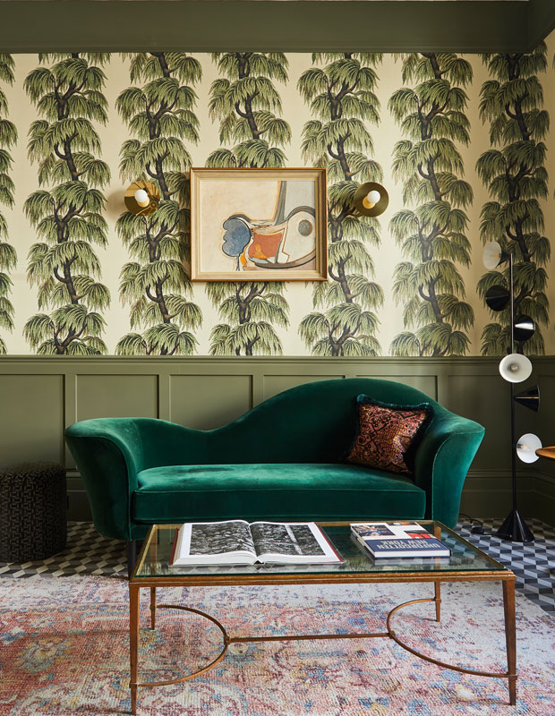 A living room with forest green hues and a green velvet couch.