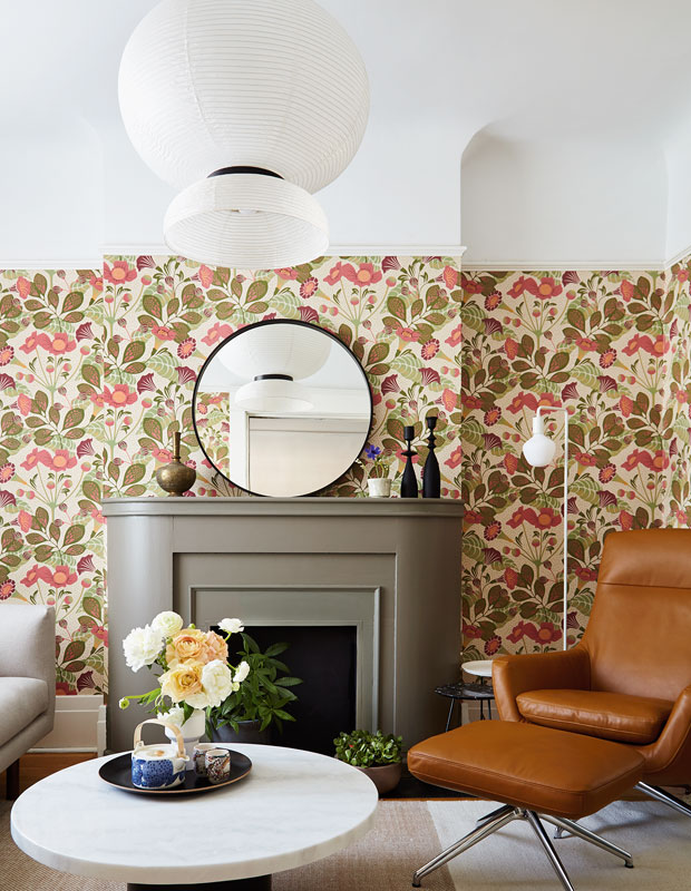 A living room with floral wallpaper and off-white couch and curtains