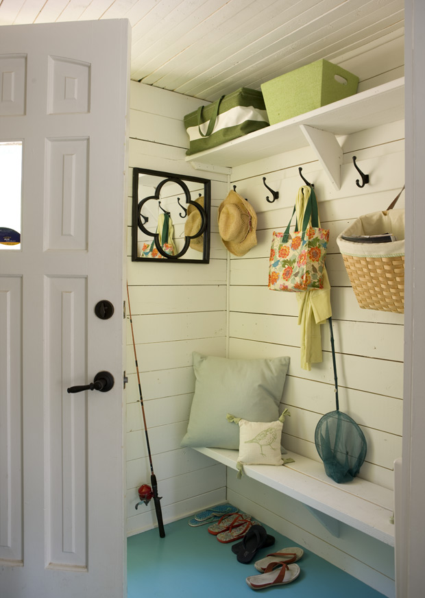 Mudroom with white vertically panelled walls and aquatic green pillow on the bench