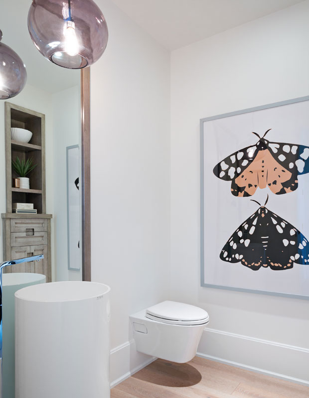 White bathroom with a purple g=light fixture and wall art of a moth