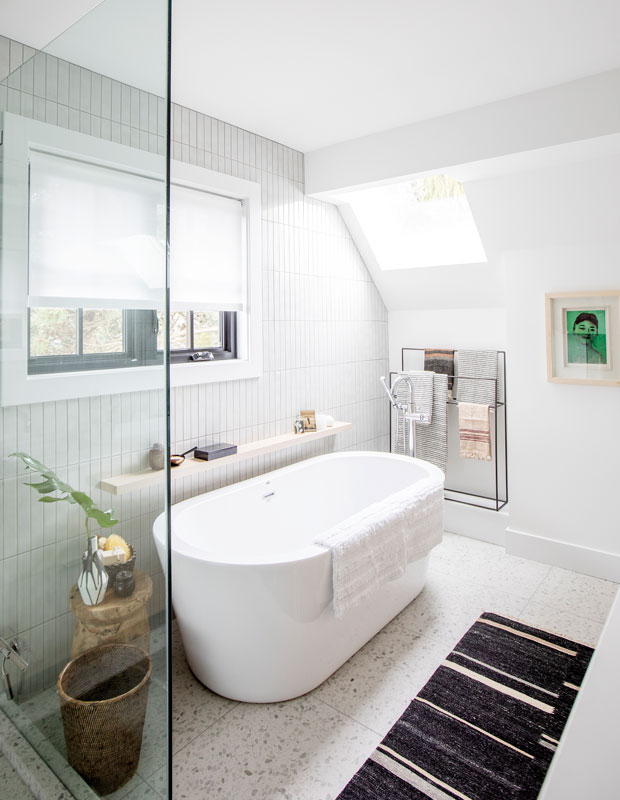 After photo of a renovated bathroom with a freestanding white tub and white vertical wall tile