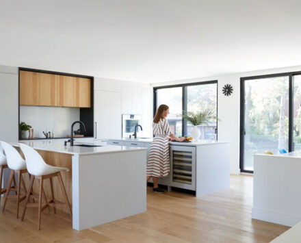 A woman stands in her bright kitchen, traying food on the white counter in the February kitchen of the month.