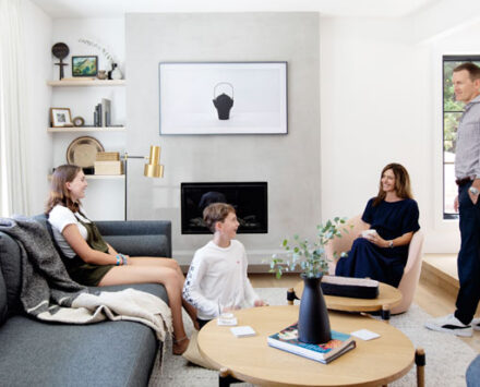 Homeowners Kelly Bremner and husband Darcy Taylor with their kids Emilia and Anderson in the newly renovated living room with a concrete fireplace