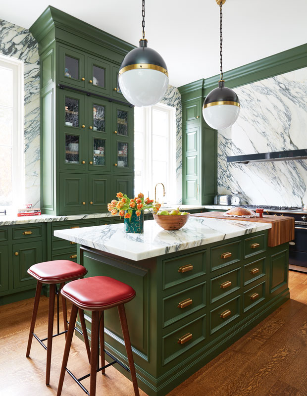 Green kitchen with round pendant lights and marble countertops.