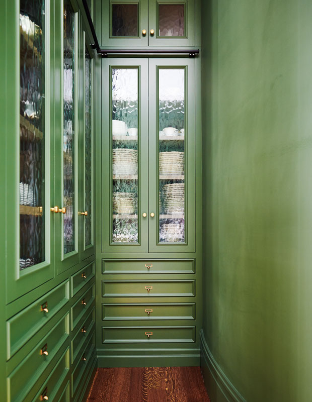 Green hallway filled with china pantries covered in rippled glass.