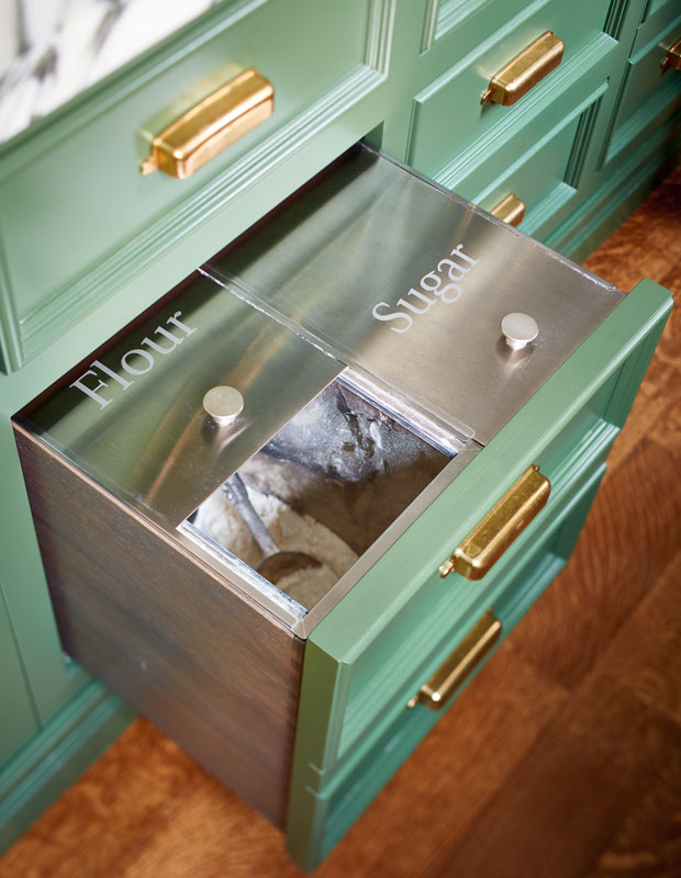 Green kitchen drawer labelled with containers for flour and sugar.