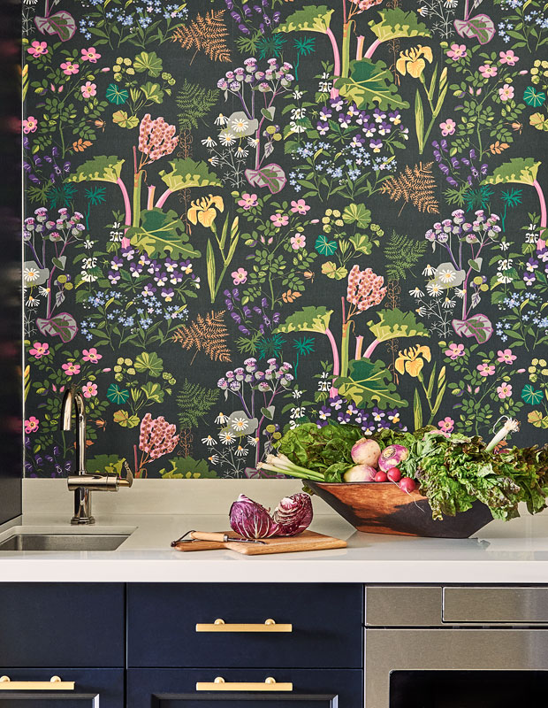 Kitchen with dark floral wallpaper and fresh fruits and vegetables on the table.