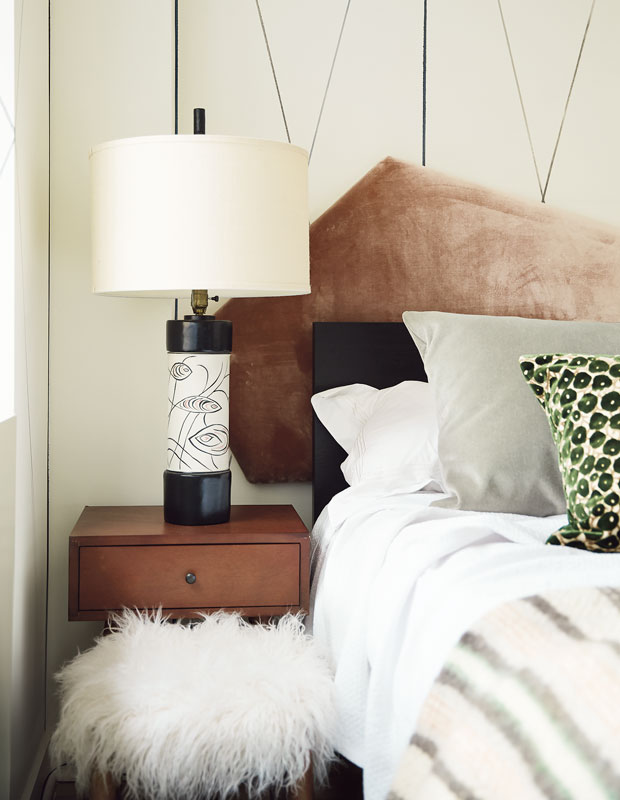 Bedside table with a white and black lamp, and geometric pattern on the wall.