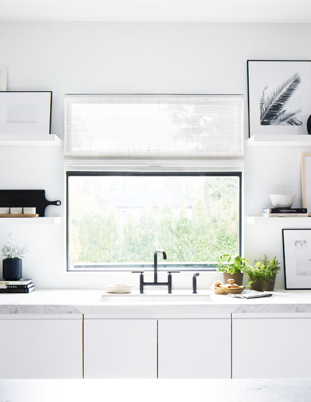 White kitchen with a large picture window above the sink looking out at trees.