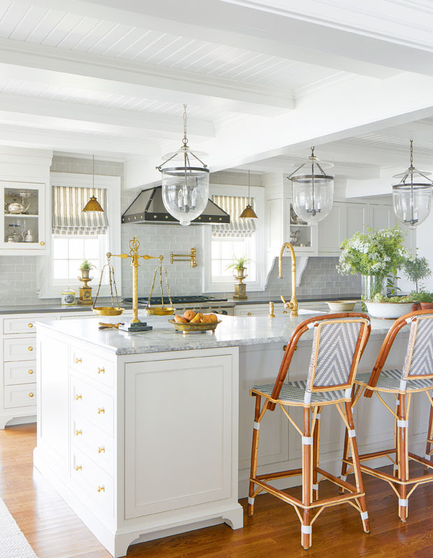 White kitchen with lantern lights hanging from the ceiling and greenery on the island.