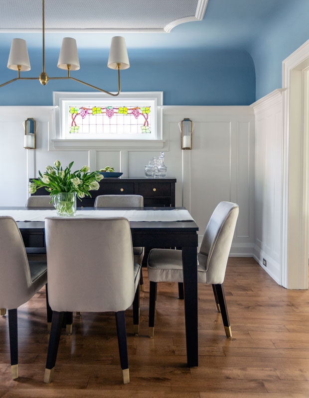 Traditional dining room with a light blue ceiling that has elegant white wainscoting in the middle