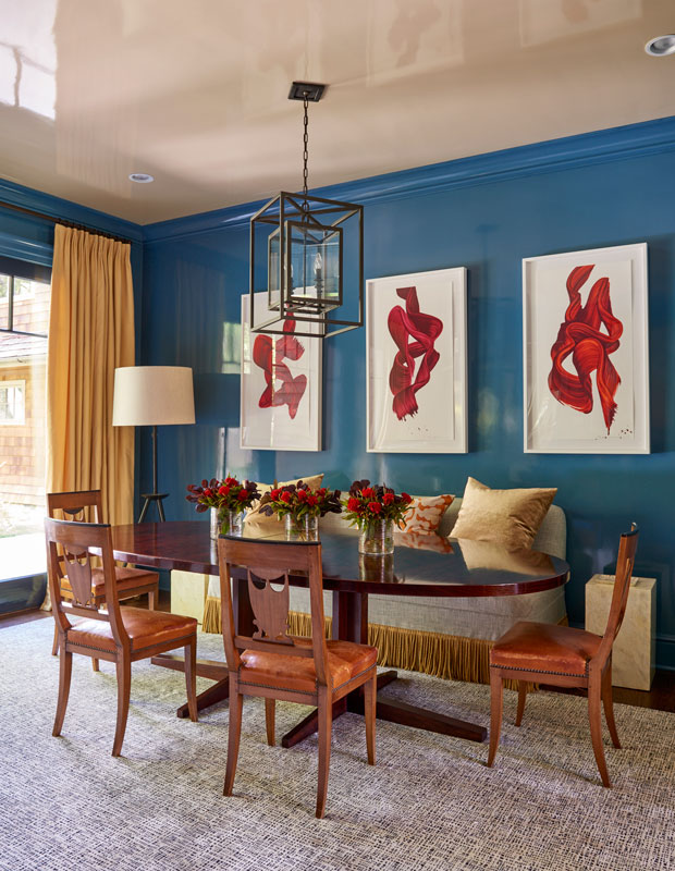 Living room with dark blue walls, dramatic red wall paintings and a reflective beige ceiling.