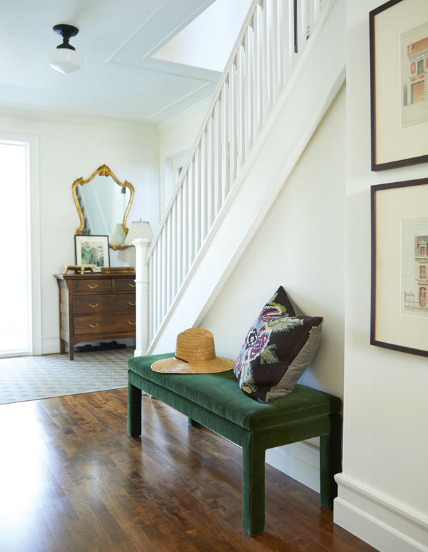 Hallway by the front door with a small upholstered bench beside the staircase.