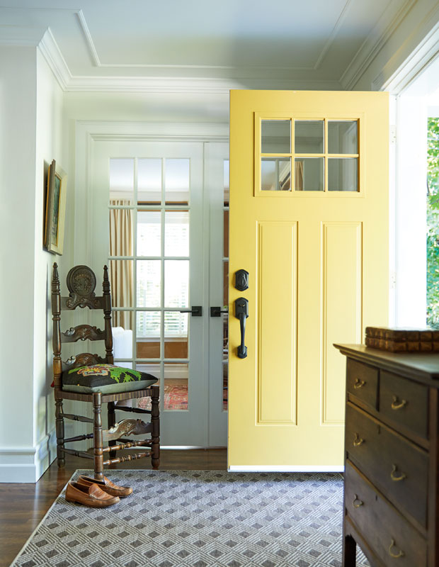 Entryway with antique chair in the corner and a buttery yellow front door.