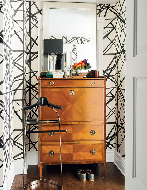 Entryway with a tall wooden dresser and black and white wallpaper.