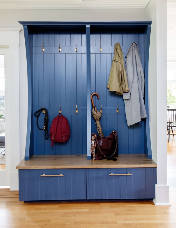Entryway with a dark blue shelf bench sith pull out drawers and coat hooks.