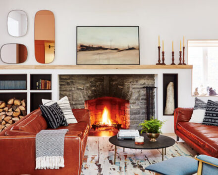 Modern Century Home with burgundy leather couches and a stone fireplace in the living room
