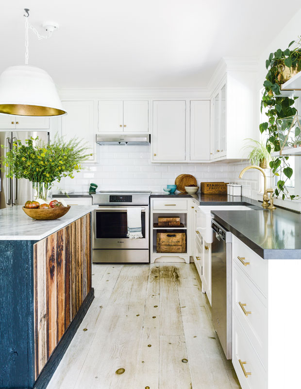 Kitchen with white tiled walls and white cabinetry and plants on the island and floating shelves.