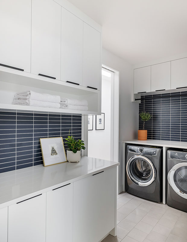 Stacked navy tile brings brings a pop of color to this sleek laundry room that offers plenty of prep space for folding.