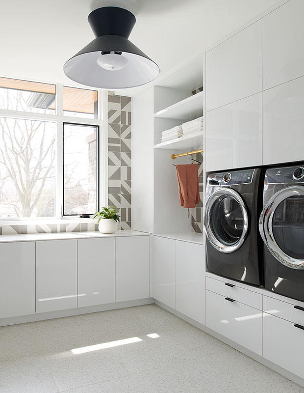 The laundry room in this Art Deco-style house features graphic wall tile, a modern black light fixture and built-in laundry storage.