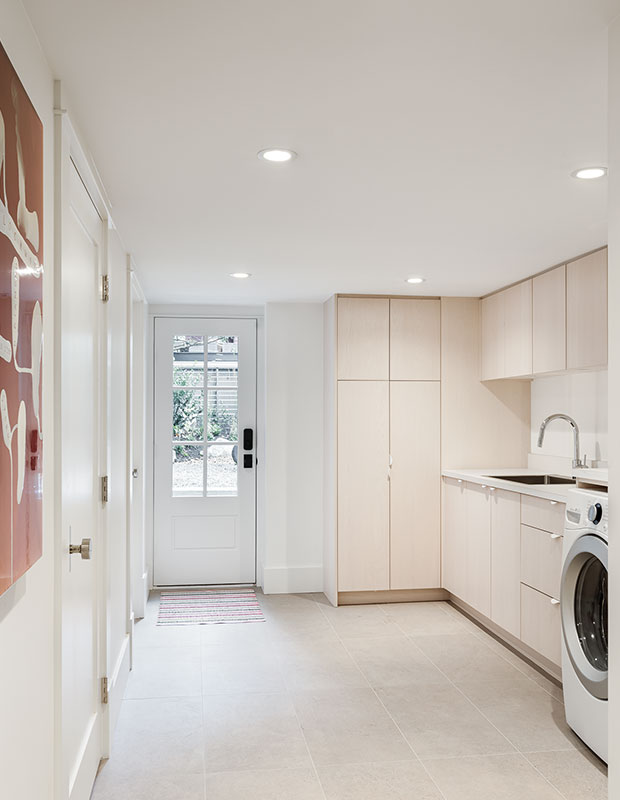 A basement laundry room with white oak cabinets to match the home's minimalist, Scandi vibe.