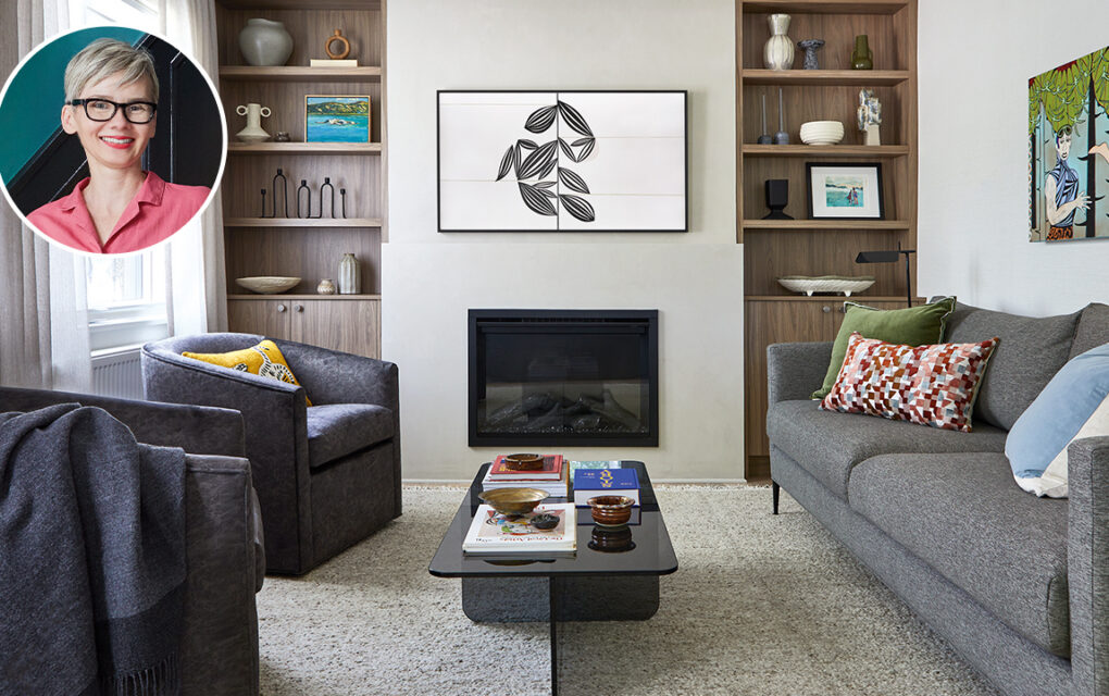 A clean and clearly new living room with grey couch, black chairs, and double cabinets which surround a TV and fireplace.