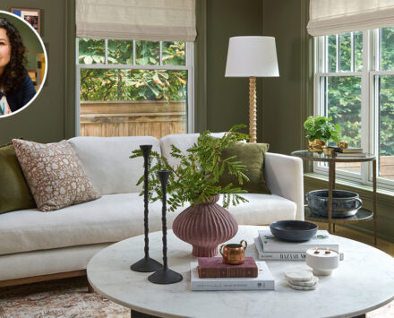 living room with deep-green walls, natural wood beams on high ceilings, and furnished with modern rounded furniture, in cool shades of white.