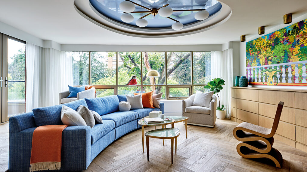 A wide shot of a living room with blue accents, large windows, and eclectic art pieces and sculptures