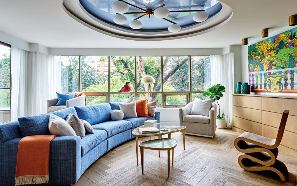 A wide shot of a living room with blue accents, large windows, and eclectic art pieces and sculptures