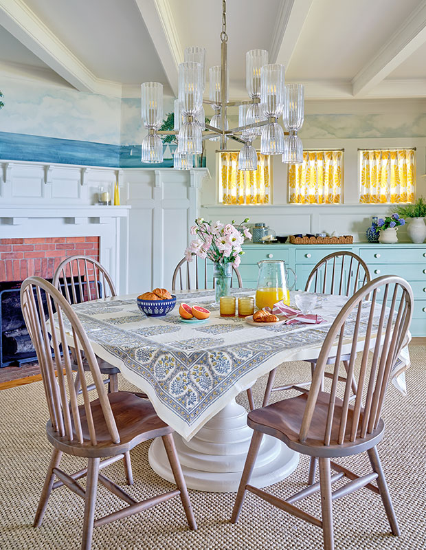 A light, airy dinning room with pops of bright colours like teal and yellow and glass elements pairs with old-school wooden furniture, creating an updated but classic space. old nova scotia home