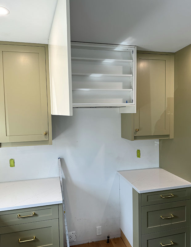 A kitchen clearly under renovation with green cabinets.