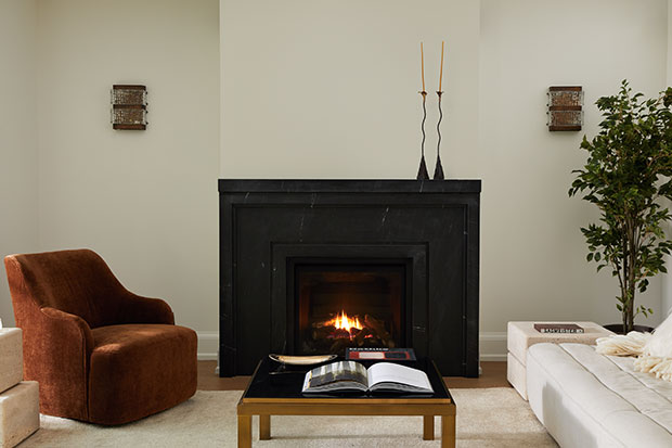 A white walled living room is contrasted by a stark black fireplace and deep orange velvet chairs. serene city retreat